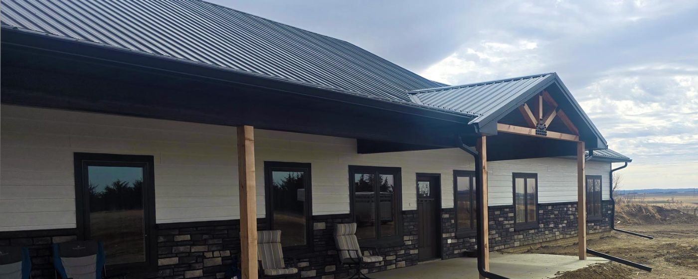 Custom home exterior with covered porch, timber posts and stone wainscot, South Dakota