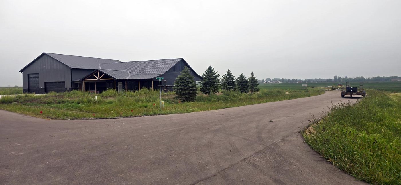 Completed custom home exterior with dark siding and metal roof on acreage near Tea, SD