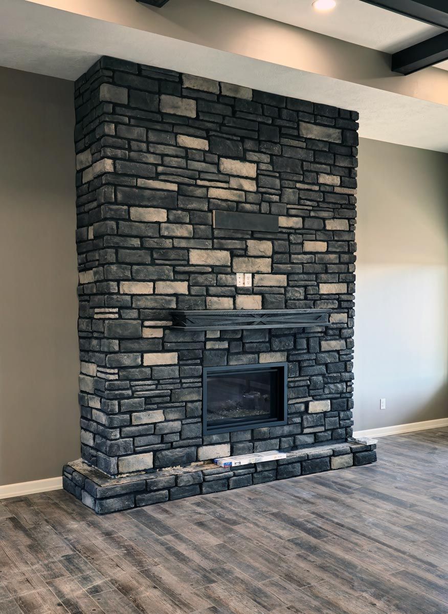 Floor to ceiling stone fireplace with timber mantel in a custom home great room