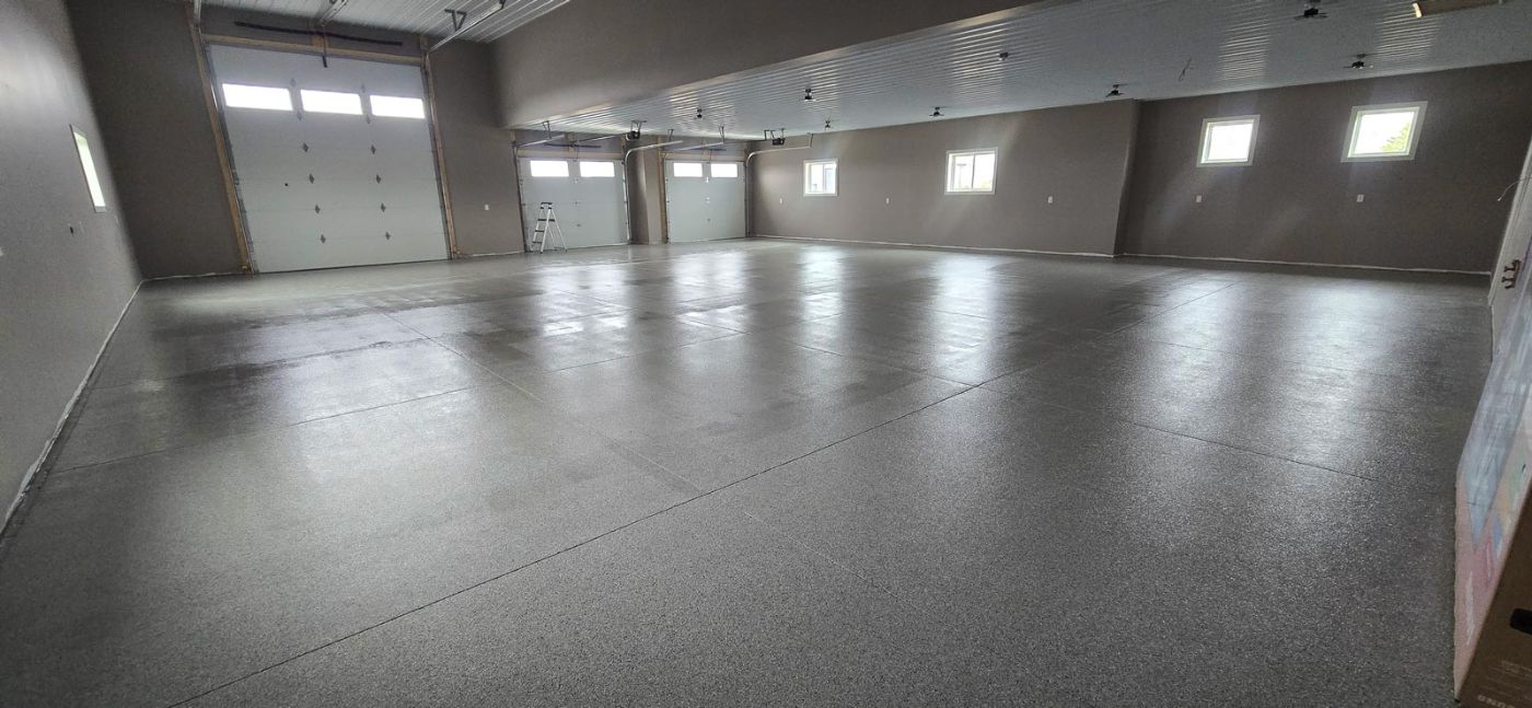 Finished shop interior with epoxy floor and overhead doors in a custom shouse