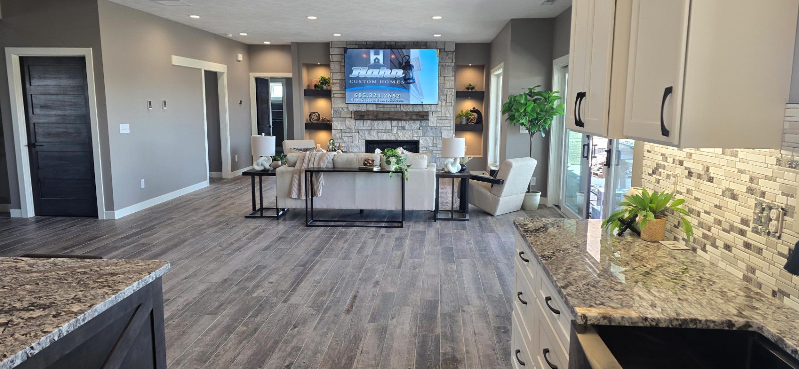 Open concept living room and kitchen with stone fireplace in a Hahn custom home